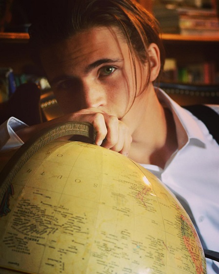 Tanner Buchanan posing as Leonardo DiCaprio behind a globe.